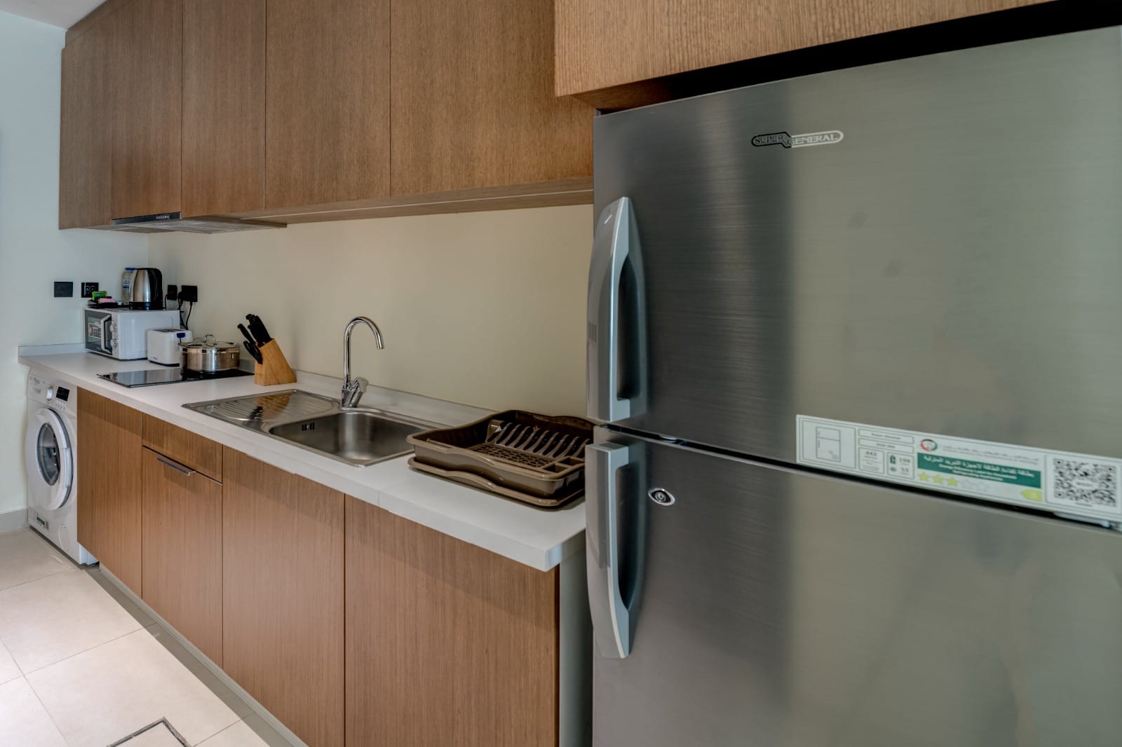 Studio kitchenette with timber cabinetry, washer and compact appliances